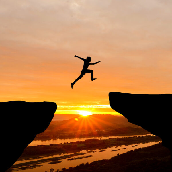 Courage man jumping over cliff on sunset background,Business con